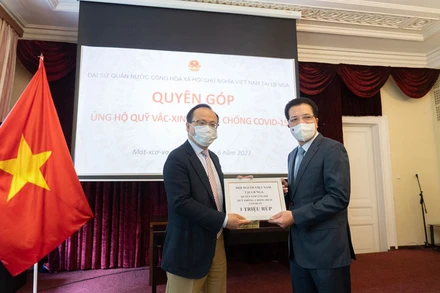 Chủ tịch Hội người Việt Nam tại LB Nga Đỗ Xuân Hoàng (bên trái) trao tượng trưng số tiền ủng hộ phòng, chống dịch Covid-19.