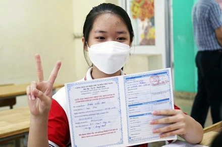 Trẻ được tiêm và nhận chứng nhận tiêm vắc-xin phòng Covid-19.