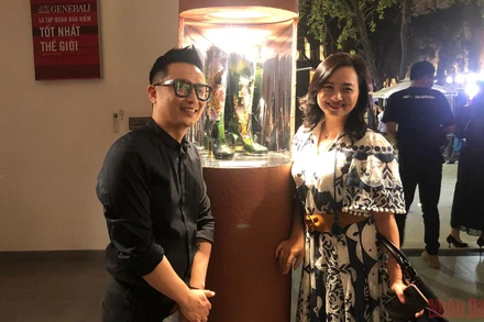 Anh Vũ Khánh Tùng (trái) bên tác phẩm của cha mình để lại.