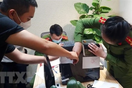 Lực lượng chức năng khám xét và niêm phong, thu giữ tài liệu tại trụ sở FLC. (Ảnh: TTXVN)