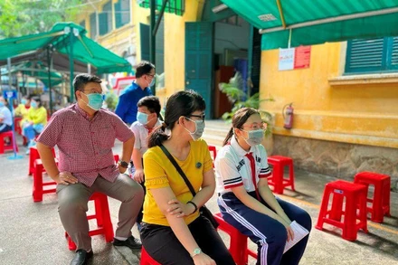 Phụ huynh và trẻ chờ đến lượt tiêm tại điểm trường THCS Hồng Bàng.