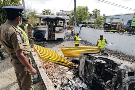Cảnh sát làm việc tại hiện trường xe ô-tô bị phóng hỏa trên đường dẫn tới nơi ở của Tổng thống Rajapaksa. (Ảnh: Reuters)