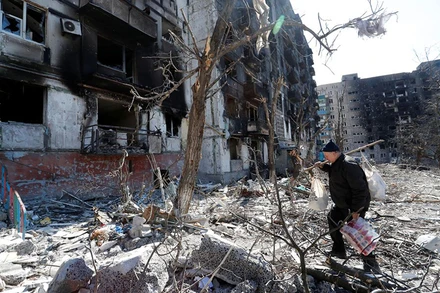 Người đàn ông đi qua sân của một tòa chung cư tại TP Mariupol, Ukraine, ngày 28/3. (Ảnh: Reuters)