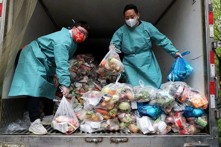 Nhân viên mặc đồ bảo hộ xếp thực phẩm lên xe tải để phân phát cho người dân. (Ảnh: China Daily)