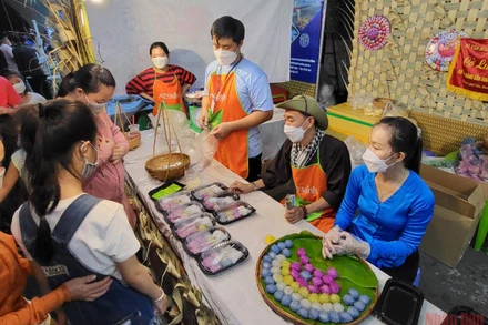 Khách tham quan thích thú thưởng thức bánh dân gian tại lễ hội.