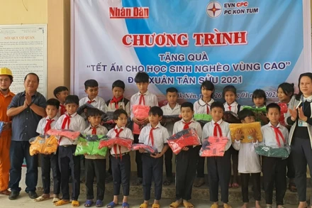 Phóng viên Báo Nhân Dân cùng đại diện Công ty Điện lực Kon Tum trao áo ấm cho các em học sinh Trường PTDT bán trú tiểu học Đắk Nên.