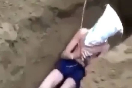 Nam thanh niên bị đẩy xuống hố, sau đó nhóm người dùng xẻng lấp đất. (Ảnh cắt từ video)