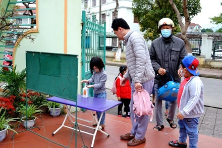 Học sinh Trường mầm non Hoa Đào thực hiện sát khuẩn tay và đeo khẩu trang trước khi vào lớp học.