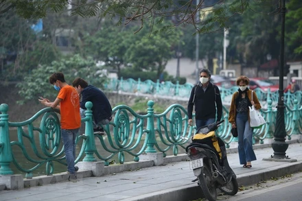 Du khách nước ngoài đi dạo bên đường quanh Hồ Tây. Ảnh: TTXVN.