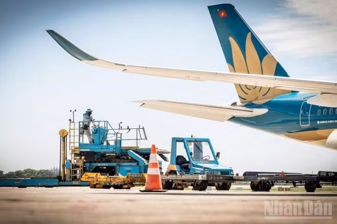 Các nhân viên phục vụ mặt đất tại sân đỗ vẫn miệt mài thực hiện các bước cuối cùng cho chuyến bay dưới nhiệt độ gần 80 độ C. (Ảnh: PHAN CÔNG)