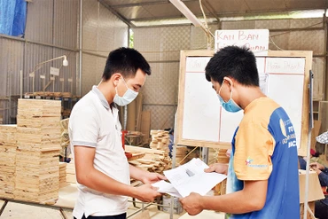 Vũ Anh Văn (bên trái) trao đổi với nhân viên về sản phẩm mới làm từ cây tre.