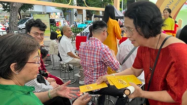 Tiến sĩ Quách Thu Nguyệt lì xì sách cho người dân tham dự chương trình.