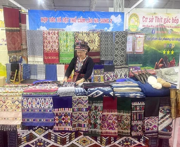 Nghệ nhân Lò Thị Viên tại gian hàng giới thiệu thổ cẩm Lào trong một triển lãm nông sản và hàng thủ công ở thành phố Điện Biên Phủ. (Ảnh VŨ THANH)
