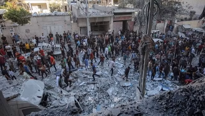Người dân Palestine đứng giữa đống đổ nát của những tòa nhà bị phá hủy sau đòn không kích của Israel tại khu vực Al-Rimal, phía tây thành phố Gaza ngày 30/8/2025. (Ảnh: THX/TTXVN)