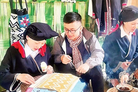 Du khách trải nghiệm nghề truyền thống vẽ sáp ong tại điểm du lịch cộng đồng bản Sưng, xã Cao Sơn.