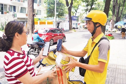 Khách hàng thanh toán không tiền mặt khi nhận hàng hóa trên đường Phạm Ngọc Thạch, Quận 3. (Ảnh THẾ ANH)