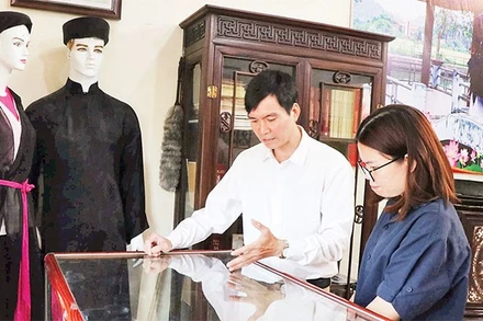 Liền anh Dương Đức Thắng giới thiệu các kỷ vật của người quan họ với du khách. 