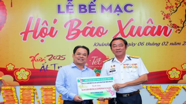 Cựu binh Trường Sa Nguyễn Văn Dũng (bên phải) tặng tượng trưng ấn phẩm Nhân Dân Xuân Ất Tỵ 2025 đến quân, dân huyện đảo Trường Sa. (Ảnh: PHONG NGUYÊN) 