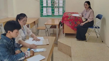 Thí sinh Thào A Dũng được hai giám thị hỗ trợ làm bài thi vào lớp 10 tại Hội đồng thi trường trung học cơ sở-trung học phổ thông Quyết Tiến (huyện Tủa Chùa). 