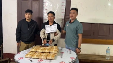 Đối tượng Tao Mùa (ở giữa) cùng tang vật 20 bánh (chứa 120 nghìn viên ma túy tổng hợp) khi bị lực lượng chức năng bắt giữ. (Ảnh: Công an Điện Biên)