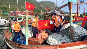 Cán bộ Bộ Tư lệnh Cảnh sát biển trao cờ Tổ quốc và quà tặng ngư dân tại cảng Bến Đầm, huyện Côn đảo, tỉnh Bà Rịa-Vũng Tàu. (Ảnh: nhandan.vn) 