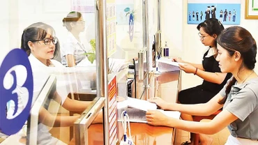 Cán bộ Bộ phận một cửa phường Thanh Xuân Nam, quận Thanh Xuân giải quyết thủ tục hành chính cho người dân. (Ảnh MỸ HÀ)