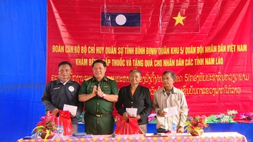 Đại tá Nguyễn Xuân Sơn, Phó Chính ủy Bộ Chỉ huy Quân sự tỉnh Bình Định tặng quà cho nhân dân ở cụm bản La Nhao, huyện Xá Mắc Khi Xay, tỉnh Attapu.