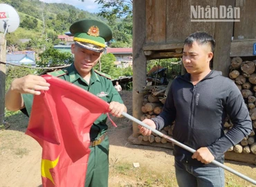 Cán bộ, chiến sĩ Đồn Biên phòng cửa khẩu Lóng Sập tặng cờ Tổ quốc cho người dân bản Bó Sập, xã Lóng Sập, huyện Mộc Châu treo chào đón ngày Tết Độc lập. 