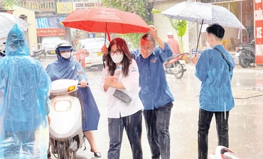 Thanh niên tình nguyện che ô, hỗ trợ thí sinh vào phòng thi.