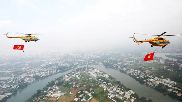 Trực thăng kéo theo cờ đỏ sao vàng và cờ Đảng ngang qua khu vực sông Đồng Nai.