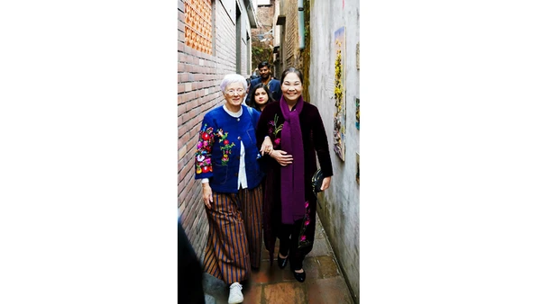 Nghệ nhân Hà Thị Vinh đón du khách nước ngoài thăm ngõ làng Bát Tràng.