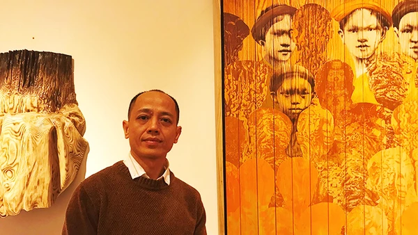 Họa sĩ Ngô Văn Sắc bên tác phẩm của mình.