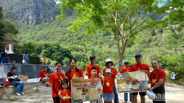 Du khách mang theo phụ san của Báo Nhân Dân về Chiến dịch Hồ Chí Minh, check-in tại thác Bản Giốc, xã Đàm Thủy, huyện Trùng Khánh, tỉnh Cao Bằng.