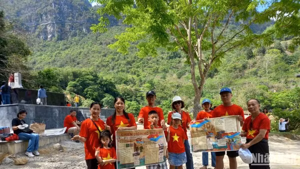 Du khách mang theo phụ san của Báo Nhân Dân về Chiến dịch Hồ Chí Minh, check-in tại thác Bản Giốc, xã Đàm Thủy, huyện Trùng Khánh, tỉnh Cao Bằng.