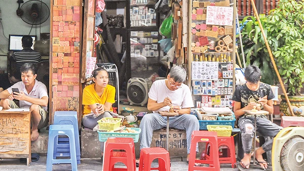 Hình ảnh ông Toàn (thứ hai từ phải sang) miệt mài khắc những con dấu gỗ đã thu hút nhiều khách du lịch khi tới phố cổ Hà Nội. 