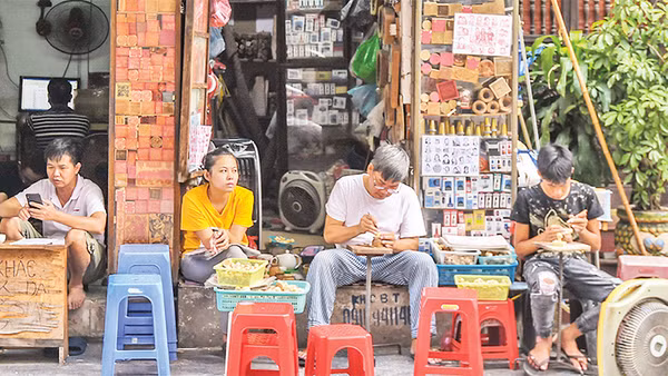 Hình ảnh ông Toàn (thứ hai từ phải sang) miệt mài khắc những con dấu gỗ đã thu hút nhiều khách du lịch khi tới phố cổ Hà Nội. 