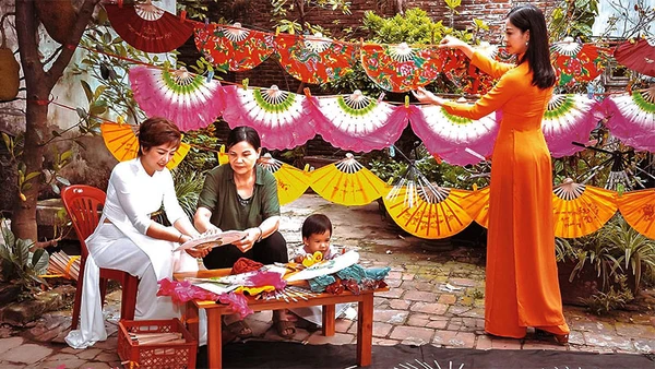 Bà Nguyễn Thị Tuấn (thứ hai, từ trái sang) giới thiệu cách làm quạt với du khách.