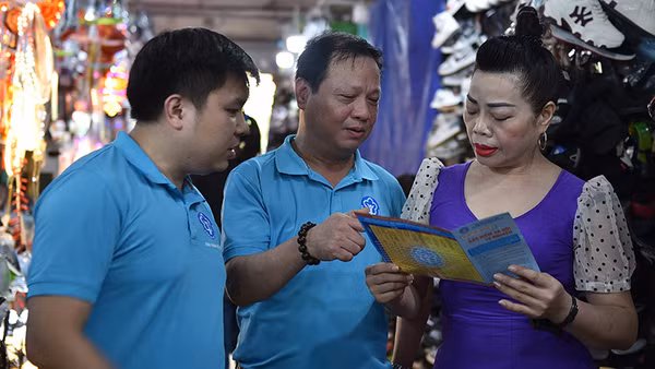 Cán bộ Bảo hiểm xã hội Hà Nội vận động người dân tham gia bảo hiểm xã hội tự nguyện, bảo hiểm y tế hộ gia đình. (Ảnh HSS) 