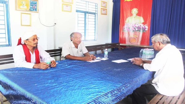 Ông Quảng Đại Thính (mặc áo vải ca-rô, giữa ảnh) gặp các bô lão trong làng để vận động xóa bỏ hủ tục lạc hậu, xây dựng đời sống văn minh.