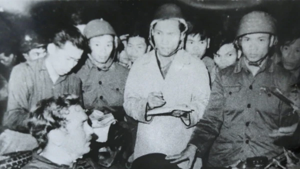 Nhà báo Phạm Thanh (người mặc áo khoác trắng) cùng nhà báo Đỗ Quảng (người đầu tiên, bên trái), phỏng vấn phi công lái máy bay B52 Mỹ bị bắt tại bãi đá Phương Liệt, Hà Nội đêm 25/12/1972. Ảnh: Bảo tàng Báo chí Việt Nam