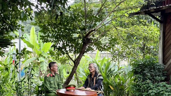 Trung tá Ating Chơn trao đổi với già làng Bríu Pố về công tác giữ gìn an ninh trật tự.