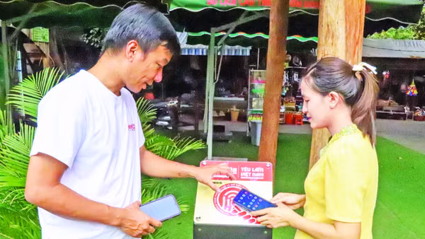 Du khách quét bảng gắn chip NFC Dự án “Yêu lắm Việt Nam” tại Trung tâm du lịch cầu treo Buôn Đôn, tỉnh Đắk Lắk. (Ảnh: KIM BẢO)