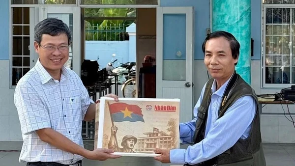 Nhà báo Trọng Duy, đại diện Văn phòng Báo Nhân Dân tại Bạc Liêu trao Phụ san đặc biệt của Báo Nhân Dân đến thầy giáo Dương Bình, Bí thư Chi bộ, Hiệu trưởng Trường Trung học phổ thông Chuyên Bạc Liêu.