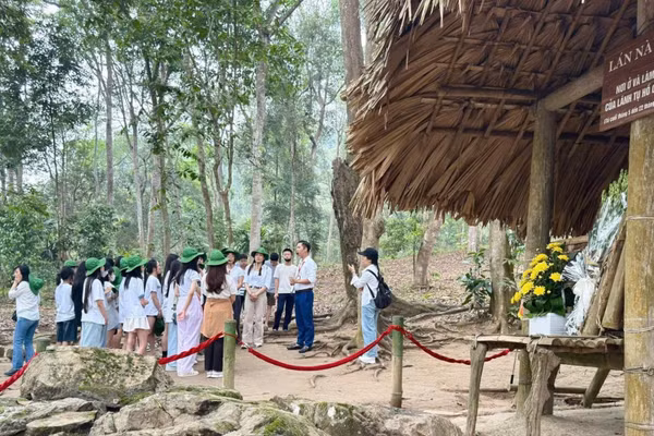 Hướng dẫn viên giới thiệu cho du khách về di tích Lán Nà Nưa, Tuyên Quang. (Ảnh: HUỆ VŨ)