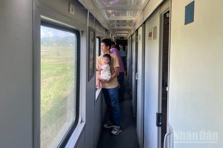 Du khách đứng ngắm cảnh qua khung cửa sổ trên tàu.