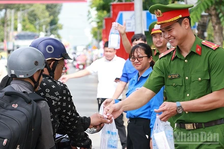 Cán bộ, chiến sĩ công an phát nước suối và khăn lạnh cho người dân về quê nghỉ lễ.