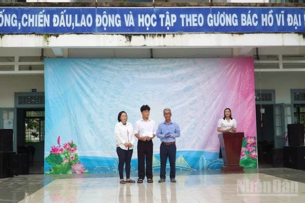 Em Trần Lê Nguyễn nhận tiền hỗ trợ của Quỹ xã hội Cỏ May tại sân trường.