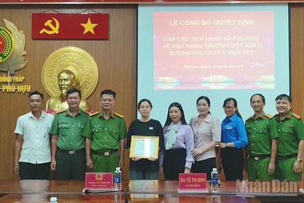 Bà Võ Thị Bình, Chủ tịch Ủy ban nhân dân xã Phú Hựu, tỉnh Đồng Tháp, (đứng thứ 5 từ phải qua trái) trao khen thưởng đột xuất cho em Phạm Nguyễn Anh Thư.