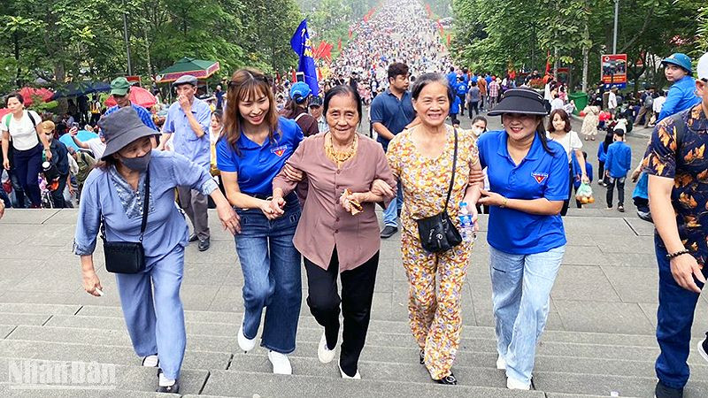 Tình nguyện viên hỗ trợ du khách cao tuổi trên đường lên Đền Hùng. 