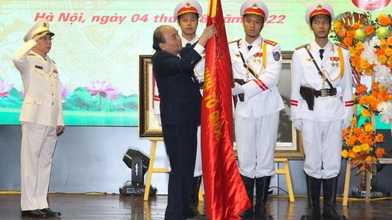 Chủ tịch nước Nguyễn Xuân Phúc gắn danh hiệu Anh hùng Lực lượng vũ trang nhân dân lên Cờ truyền thống của đơn vị. (Ảnh: Báo CAND)